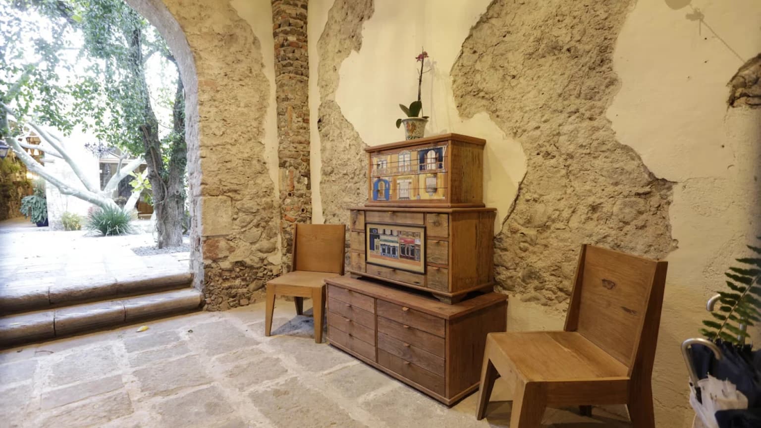 A corner with hand-painted antique furniture, wooden chairs and the exposed stone wall