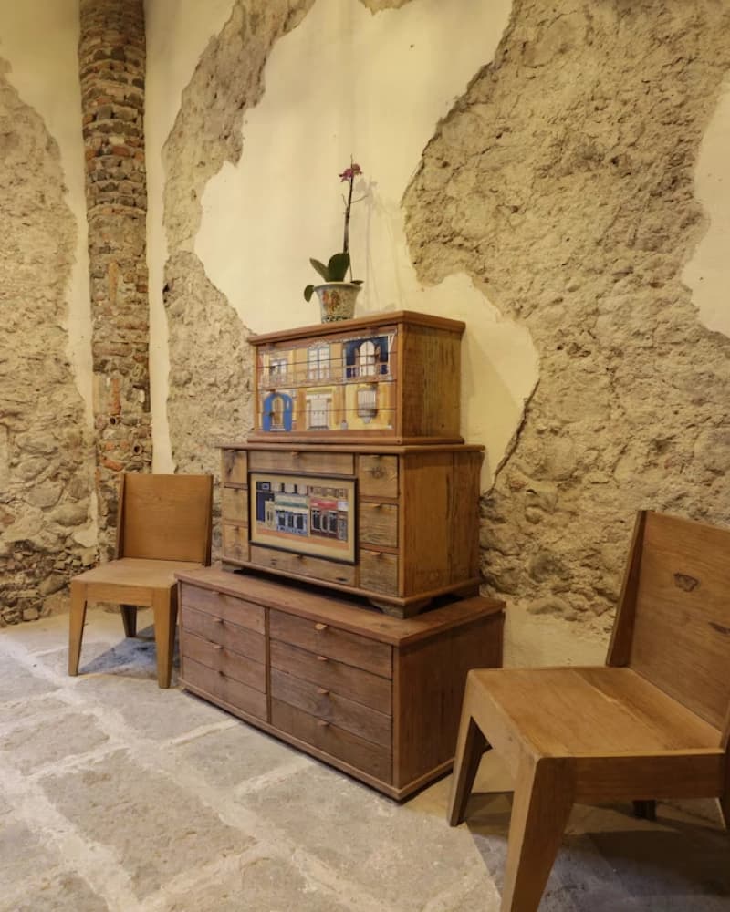 A corner with hand-painted antique furniture, wooden chairs and the exposed stone wall