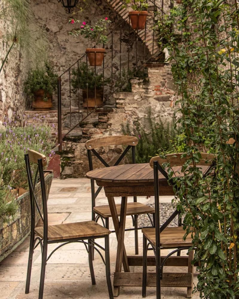 A garden corner with a wooden table and chairs, among lavender plants and a stone stairway